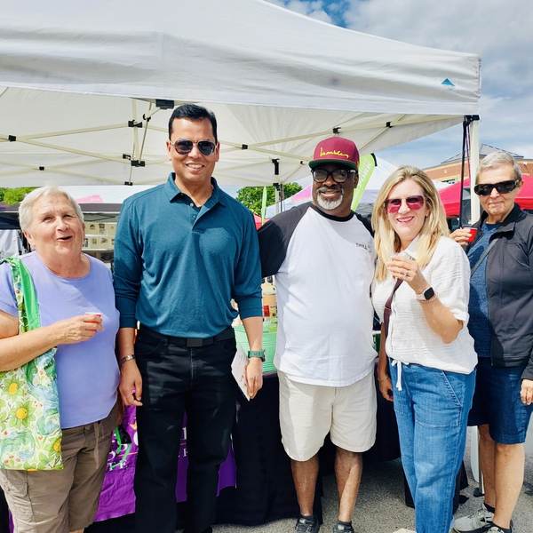 Arvind Choudhary standing with a group of Oakville residents at an outdoor community market.